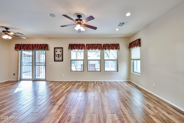 unfurnished room featuring visible vents, baseboards, wood finished floors, and a ceiling fan