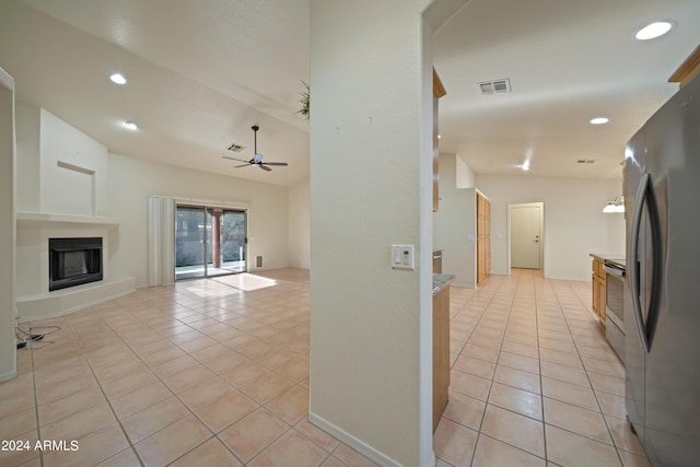 interior space with electric stove, ceiling fan, refrigerator, and light tile patterned floors