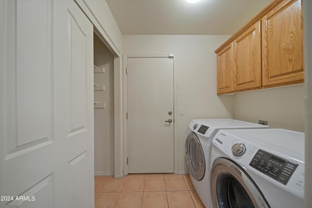 laundry area featuring washer and clothes dryer, cabinets, and light tile patterned flooring