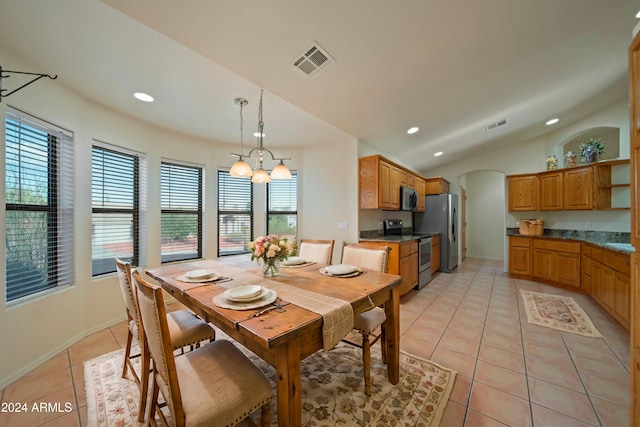 tiled dining room with vaulted ceiling and a notable chandelier