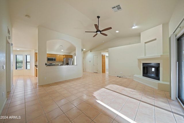 unfurnished living room with ceiling fan, vaulted ceiling, and light tile patterned floors