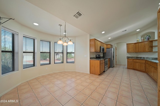 kitchen with appliances with stainless steel finishes, dark stone countertops, light tile patterned flooring, decorative light fixtures, and vaulted ceiling