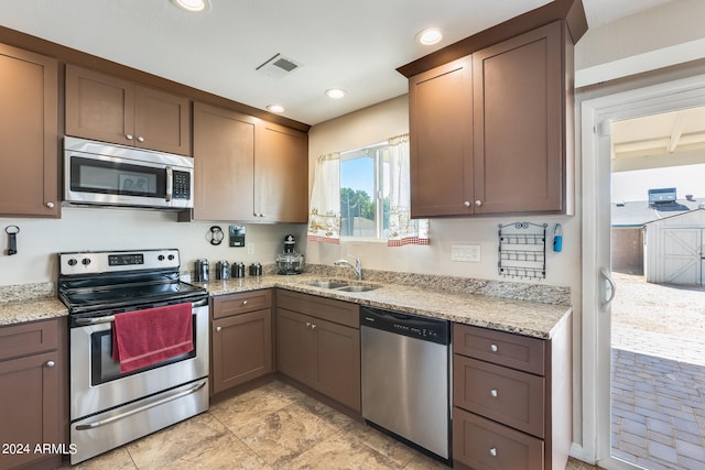 kitchen with light stone counters, beam ceiling, sink, and stainless steel appliances