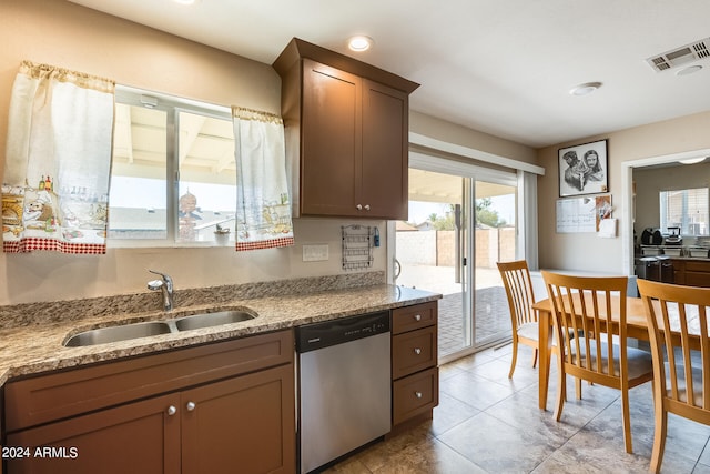 kitchen with stainless steel dishwasher, a healthy amount of sunlight, light stone countertops, and sink