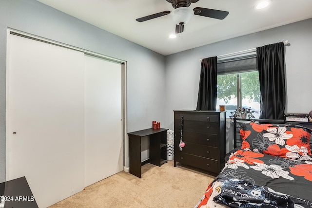 bedroom with a closet, light colored carpet, and ceiling fan