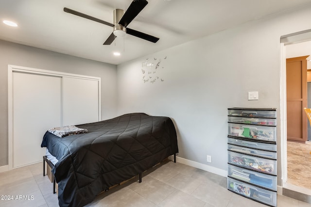 tiled bedroom with ceiling fan and a closet