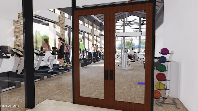 exercise room with a towering ceiling and carpet floors