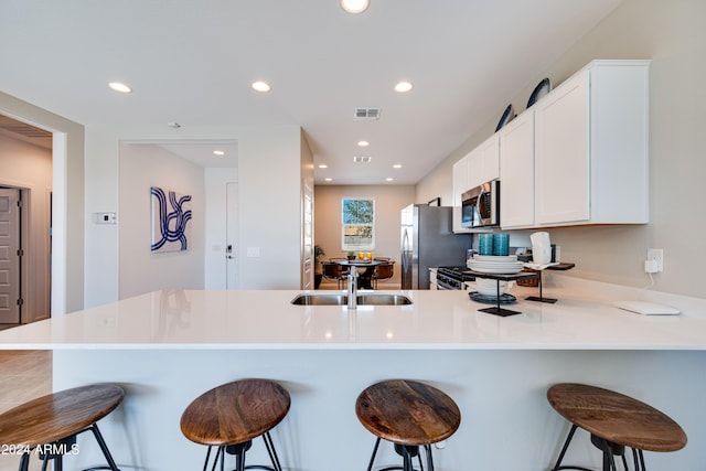 kitchen with stainless steel appliances, sink, a kitchen bar, and kitchen peninsula