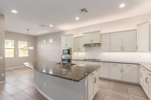 kitchen featuring white cabinetry, sink, and a center island with sink