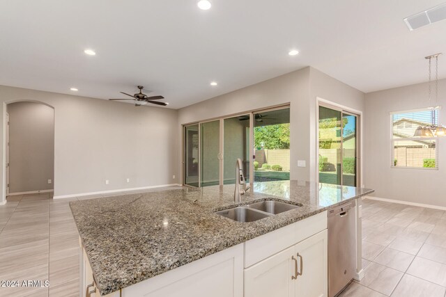 kitchen with sink, light stone countertops, decorative light fixtures, white cabinets, and dishwasher