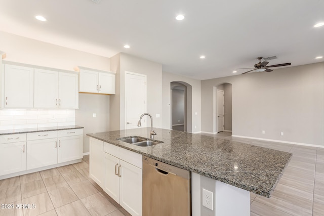 kitchen with white cabinetry, sink, dark stone counters, stainless steel dishwasher, and an island with sink