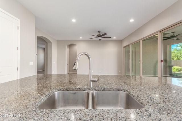 kitchen with stone counters, sink, and ceiling fan