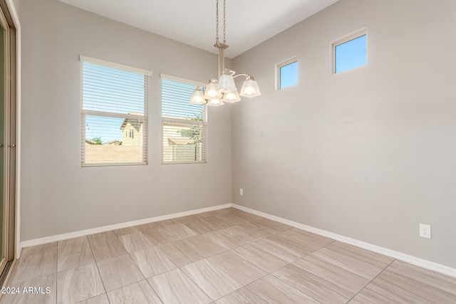 spare room with a healthy amount of sunlight and an inviting chandelier