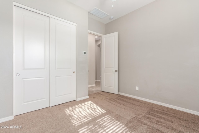 unfurnished bedroom with light colored carpet and a closet