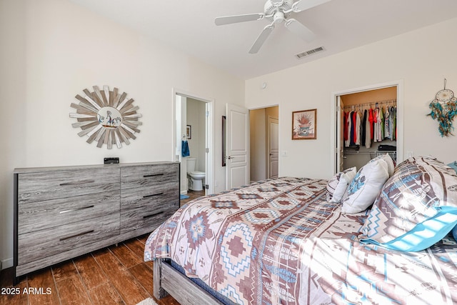 bedroom with ceiling fan, ensuite bathroom, dark hardwood / wood-style floors, a spacious closet, and a closet