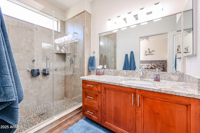 bathroom featuring a shower with shower door and vanity