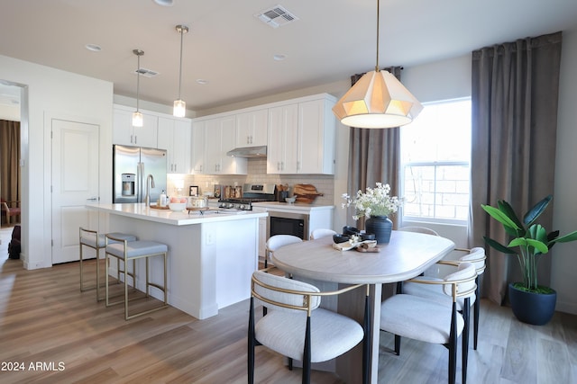 kitchen featuring under cabinet range hood, visible vents, light countertops, appliances with stainless steel finishes, and backsplash