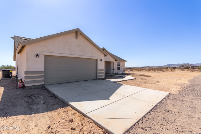 view of front of property with a garage, a mountain view, and central AC unit