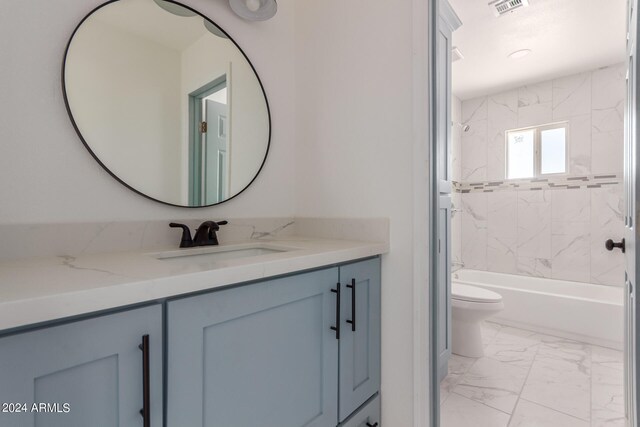 full bathroom featuring tiled shower / bath, vanity, and toilet