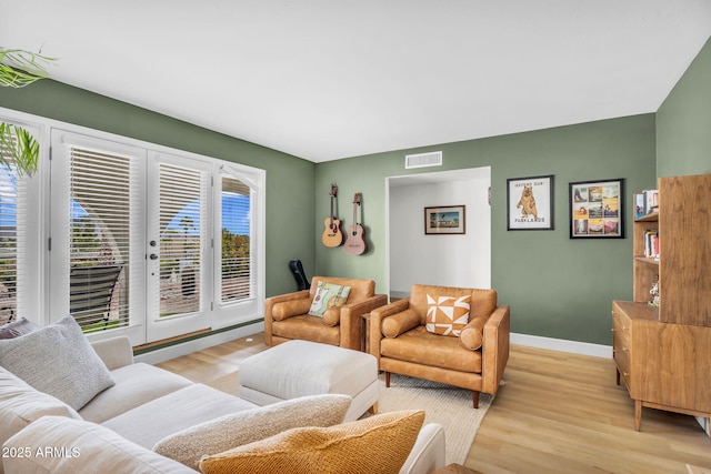 living room featuring visible vents, light wood-type flooring, and baseboards