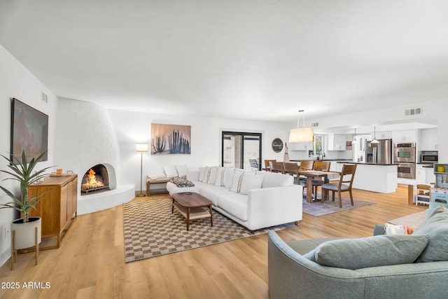 living area featuring light wood-style floors, visible vents, and a large fireplace