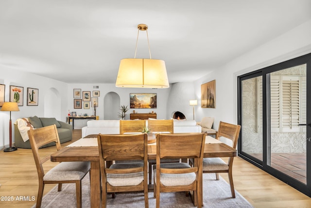 dining area featuring arched walkways and light wood-style floors