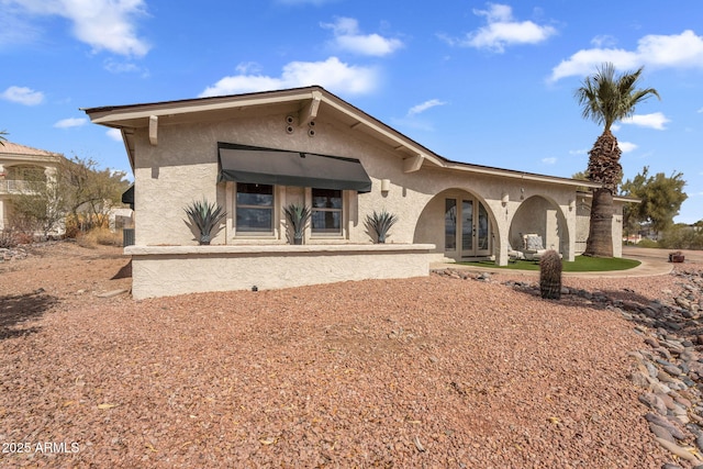 back of house featuring stucco siding and french doors