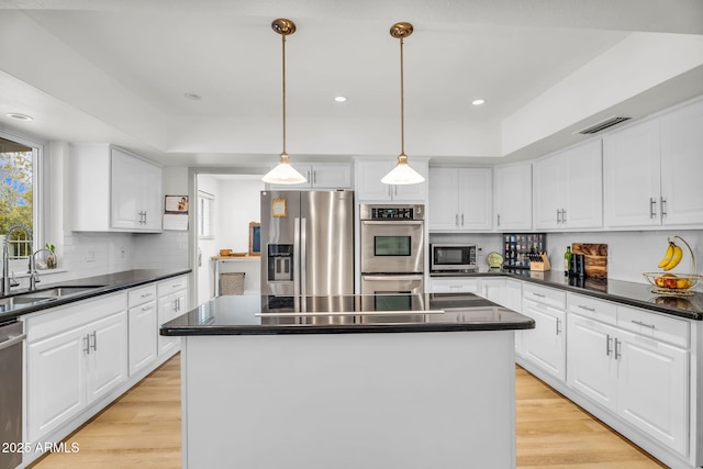 kitchen with white cabinetry, dark countertops, light wood-style floors, and stainless steel appliances