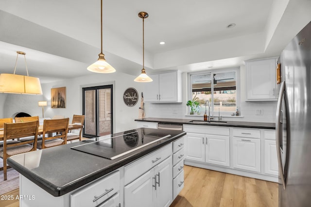 kitchen featuring a sink, backsplash, dark countertops, appliances with stainless steel finishes, and a raised ceiling