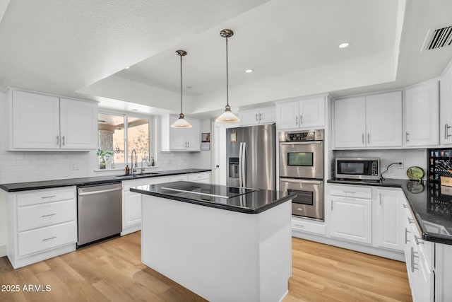 kitchen featuring a sink, a tray ceiling, appliances with stainless steel finishes, and visible vents