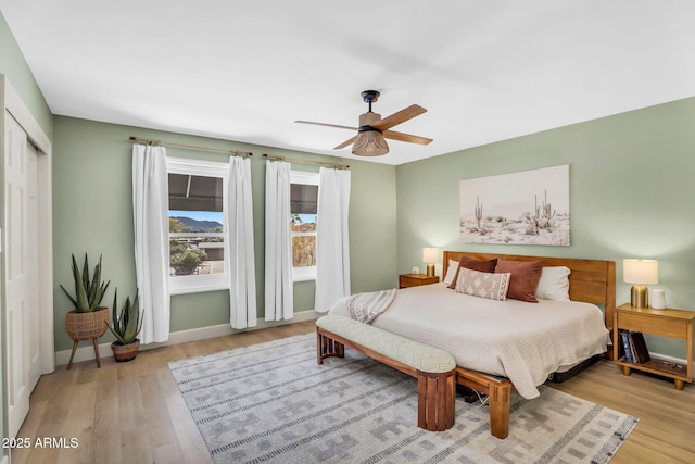 bedroom with a ceiling fan, wood finished floors, baseboards, and a closet