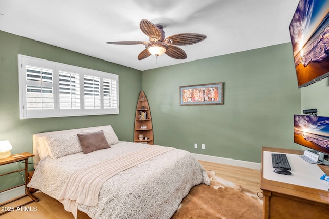 bedroom featuring a ceiling fan, baseboards, and wood finished floors