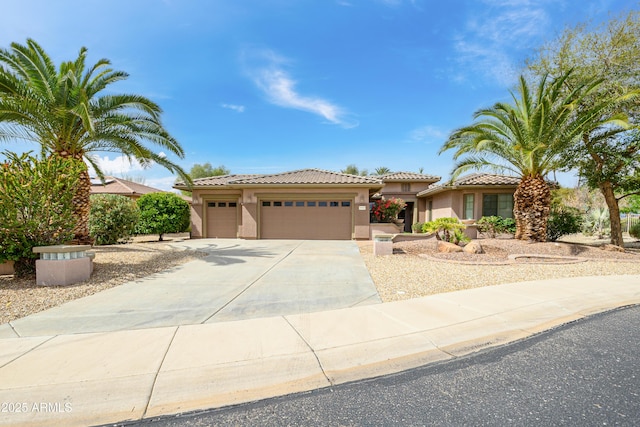 view of front of property with stucco siding, a tiled roof, an attached garage, and driveway