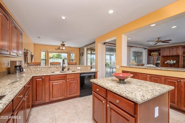 kitchen with a ceiling fan, a sink, black dishwasher, a center island, and light stone countertops