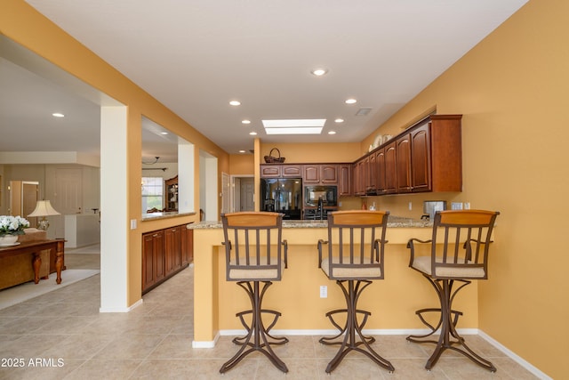 kitchen featuring a breakfast bar, recessed lighting, a peninsula, and black appliances