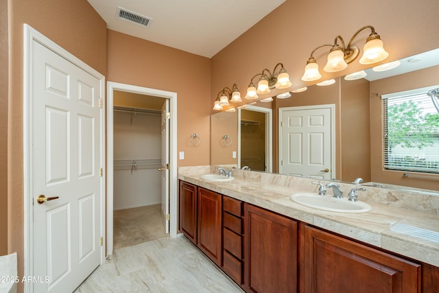 full bath with a walk in closet, double vanity, visible vents, and a sink