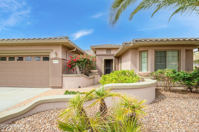 mediterranean / spanish house featuring stucco siding, an attached garage, driveway, and a tile roof