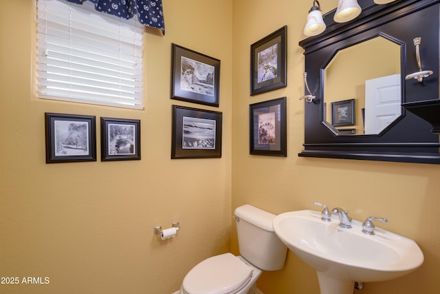 half bath featuring toilet and a sink