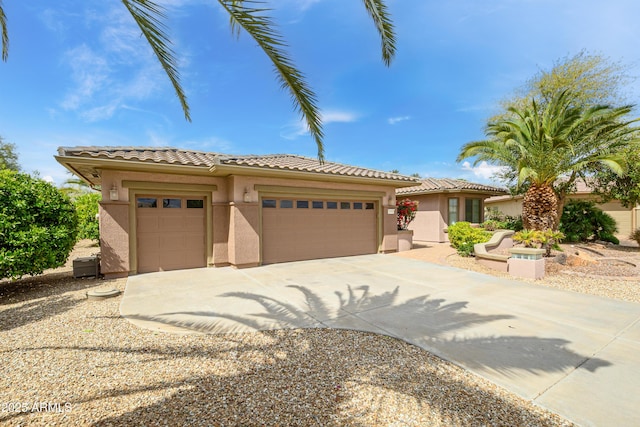 view of front of home with a tiled roof, an attached garage, driveway, and stucco siding