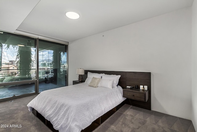 bedroom featuring a wall of windows, dark carpet, and access to exterior