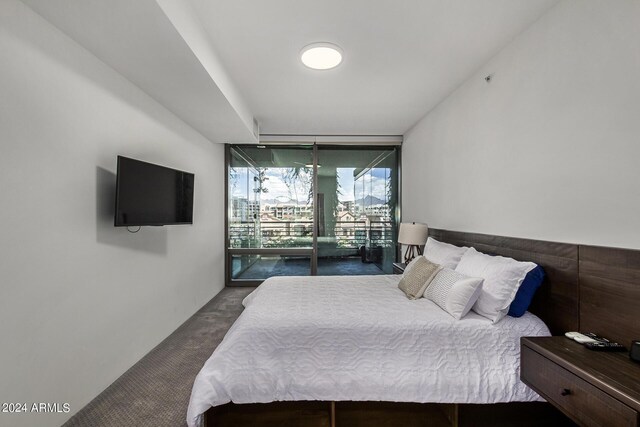 bedroom with access to outside, expansive windows, and dark colored carpet