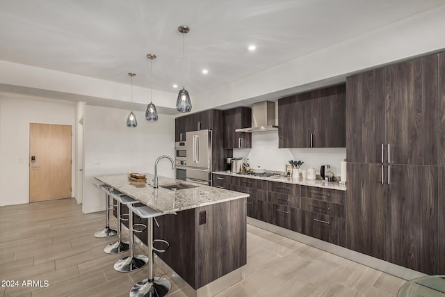 kitchen with wall chimney exhaust hood, modern cabinets, a sink, and a kitchen breakfast bar