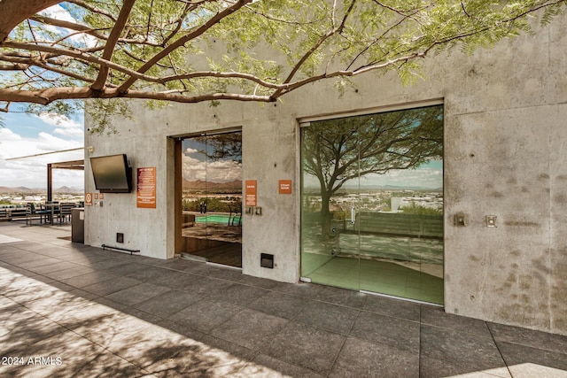 view of exterior entry with stucco siding and a patio