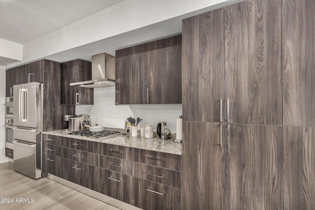 kitchen featuring appliances with stainless steel finishes, dark brown cabinetry, wall chimney range hood, and modern cabinets