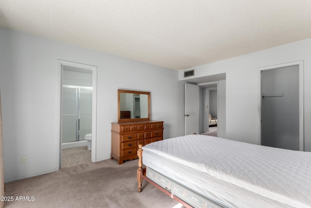 bedroom with ensuite bathroom, a textured ceiling, a spacious closet, light colored carpet, and a closet