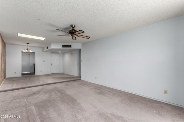 carpeted empty room with ceiling fan with notable chandelier and a textured ceiling