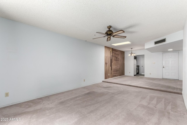 carpeted spare room featuring ceiling fan with notable chandelier and a textured ceiling