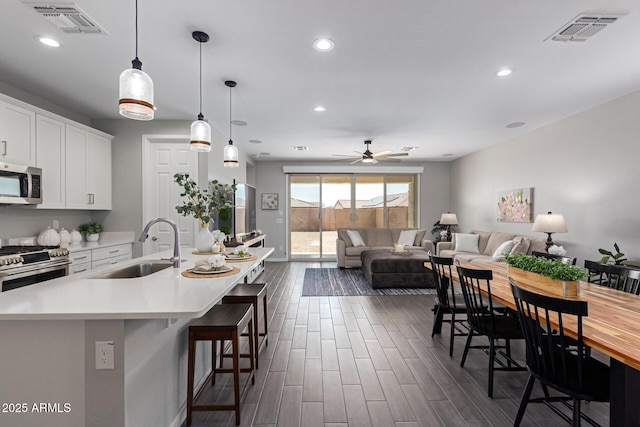 kitchen featuring a kitchen bar, an island with sink, appliances with stainless steel finishes, white cabinets, and sink