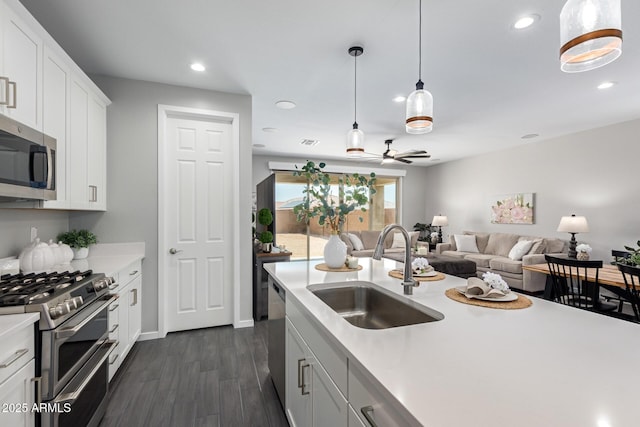 kitchen featuring white cabinetry, appliances with stainless steel finishes, dark wood-type flooring, pendant lighting, and sink