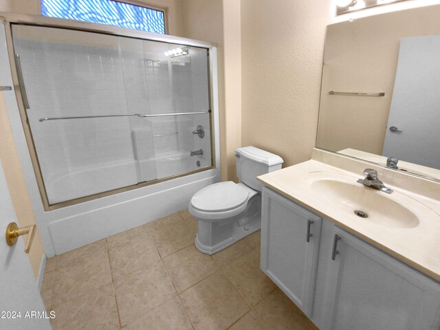 full bathroom featuring tile patterned flooring, bath / shower combo with glass door, toilet, and vanity